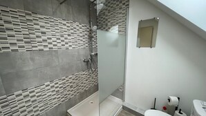 Ein modernes Badezimmer mit Dusche, Toilette und einem kleinen Spiegel.