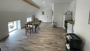 Eine geräumige Küche mit Mikrowelle, Backofen und kleinem Kühlschrank. Es gibt eine Essecke mit Tisch und Stühlen sowie ein Fenster mit Blick ins Freie.