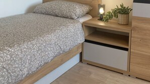 A bedroom with a bed, bedside table, lamp, and a potted plant. - Spacious 2-bedroom apartment in Lučenec (Banskobystrický kraj)