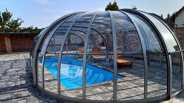 A covered patio area with a pool, lounge chairs, and a brick wall. - Spacious 2-bedroom apartment in Lučenec (Banskobystrický kraj)