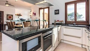A modern kitchen with a central island, built-in oven, and a large window.