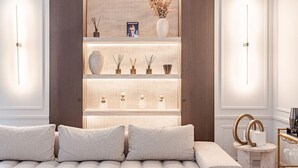 Una sala de estar moderna con un sofá, estanterías decorativas e iluminación instalada en la pared.