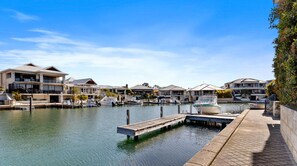 A marina with boats docked, a wooden dock, and modern houses along the water.