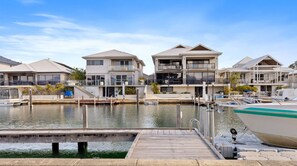 A marina with modern waterfront homes, docked boats, and a wooden dock.