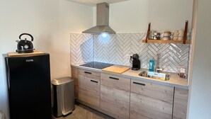 Et moderne køkken med et sort køleskab, en indbygget kogeplade, træskabe og et backsplash i et fiskebensmønster.