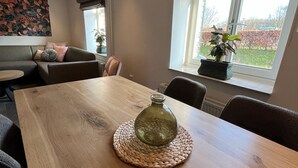 Et spiseområde med et træbord, en vævet bordskåner og en glasvase.