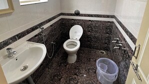 A bathroom with a toilet, sink, and shower. - Hotel Lalitha Comfort (Bengaluru)