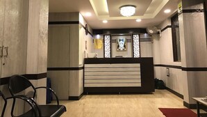 A hotel reception area with a modern design, featuring a reception desk, seating area, and a decorative wall. - Hotel Lalitha Comfort (Bengaluru)