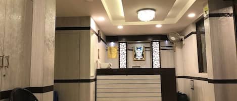 A hotel reception area with a modern design, featuring a reception desk, seating area, and a decorative wall.