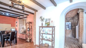 A dining area with a wooden table and chairs, a chandelier, and a brick wall with a tiled backsplash. - Apartment in Andalusia with Scenic Views (Peñaflor)