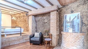 A rustic interior with exposed brick walls, a wooden bench, a black leather chair, and a small table with a vase. - Apartment in Andalusia with Scenic Views (Peñaflor)