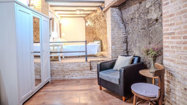 A cozy room with a wooden floor, a black sofa, a small round table, and a white cabinet. - Apartment in Andalusia with Scenic Views (Peñaflor)