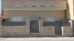 Un bâtiment à deux étages, doté d’un toit plat, d’un balcon à l’étage supérieur et d’une entrée fermée par un portail.