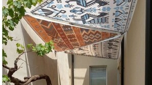 Une terrasse avec un parasol à motifs, une petite table et deux chaises.