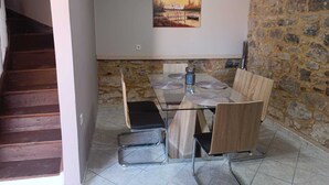 Ein Essbereich mit Tisch und Stühlen, einem Gemälde an der Wand und einer Steinwand.