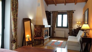 A cozy room with a fireplace, a sofa, a chair, and a bed.