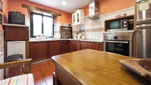 A kitchen with wooden cabinets, a wooden countertop, a microwave, an oven, and a refrigerator.