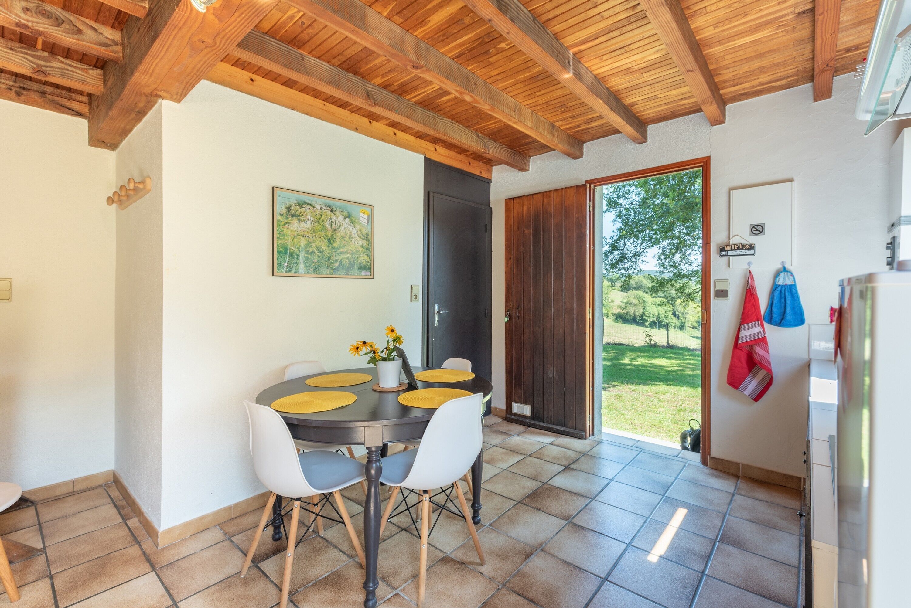 Uma sala de jantar com uma mesa redonda, cadeiras e vista para o exterior.