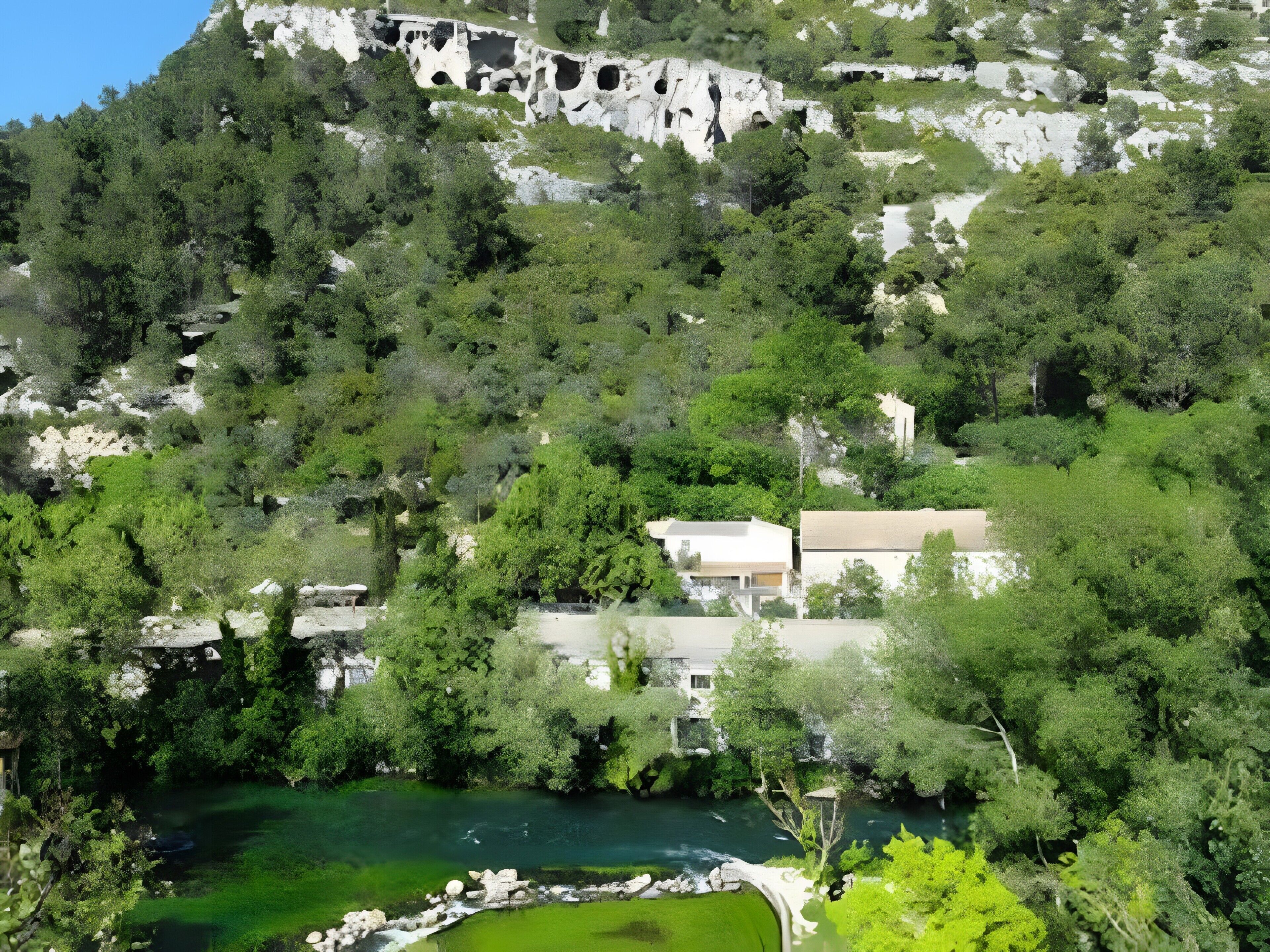 Eine gebirgige Landschaft mit einem Fluss, Bäumen und einem Gebäude mit flachem Dach.