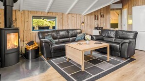 A cozy room with a black leather sofa, a wooden coffee table, and a wood-burning stove. - "Kai" - 400m from the sea by Interhome (Sydals)
