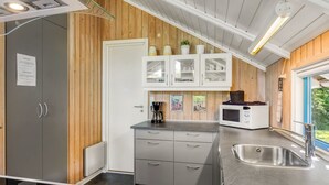 A modern kitchen with wooden walls, white cabinets, and a stainless steel sink. - "Kai" - 400m from the sea by Interhome (Sydals)