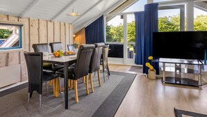 A modern dining area with a large table, chairs, and a television. - "Kai" - 400m from the sea by Interhome (Sydals)