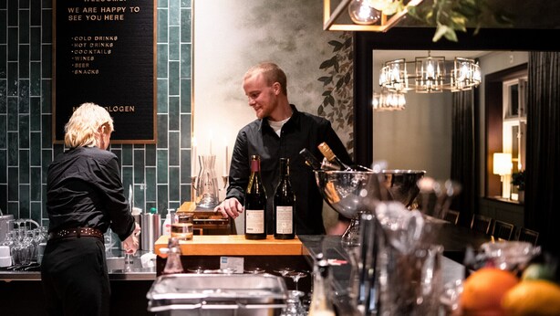 Un espace bar avec un tableau affichant la carte des boissons froides, des boissons chaudes, des cocktails, des vins, des bières et des en-cas.
