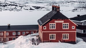 Un bâtiment rouge avec une enseigne sur laquelle on peut lire « METOROLOGEN », dans un paysage enneigé.