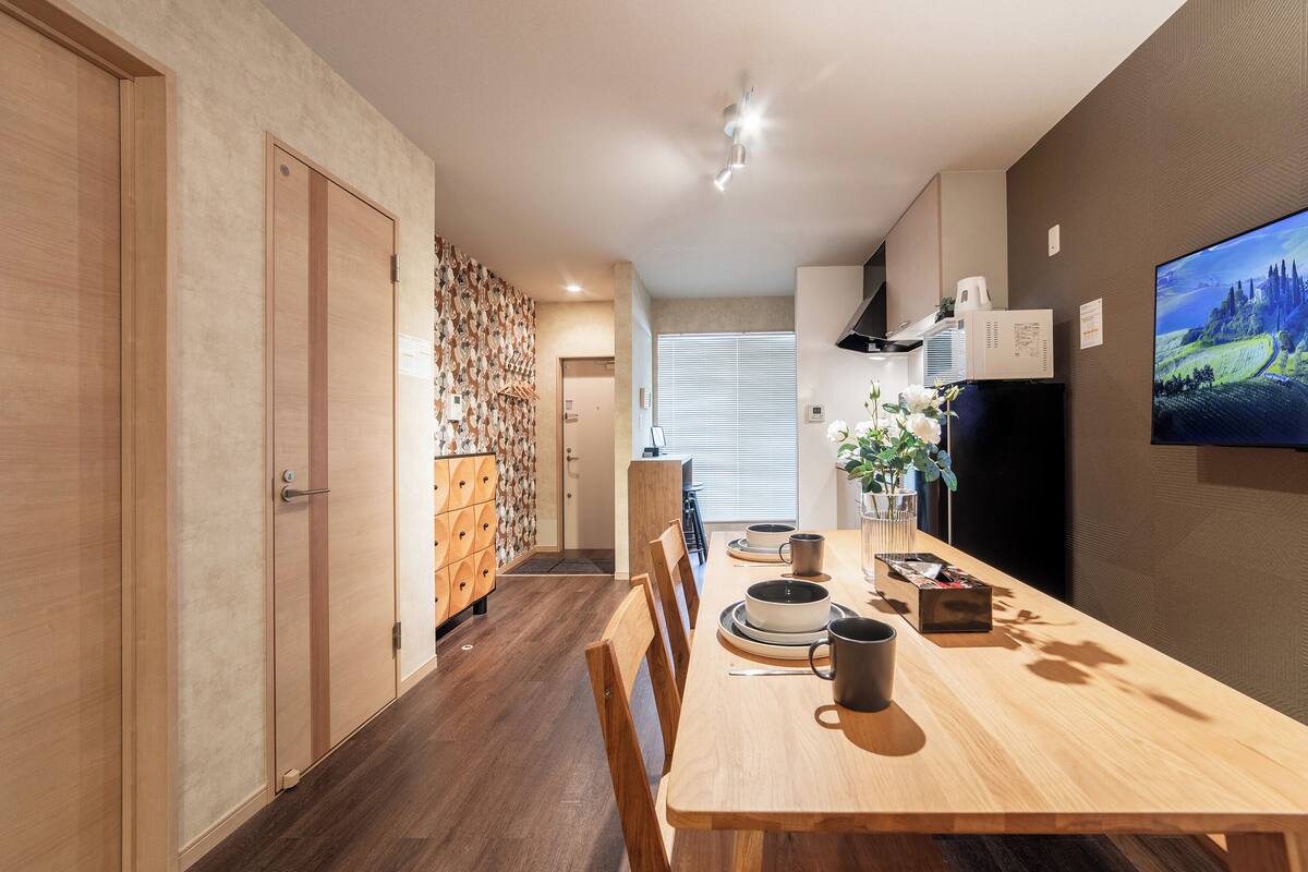 A modern dining area with a wooden table, chairs, and a television on the wall.