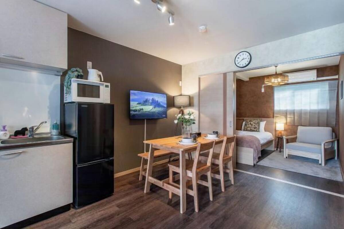 A compact living space with a kitchenette, a dining area, a bed, and a small sitting area.