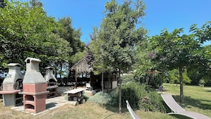 Un patio con equipo para cocinar al aire libre, una mesa de madera y una silla de descanso.