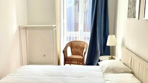 A hotel room with a bed, a chair, a lamp, and a window with curtains. - River view over Tage (Lisboa)