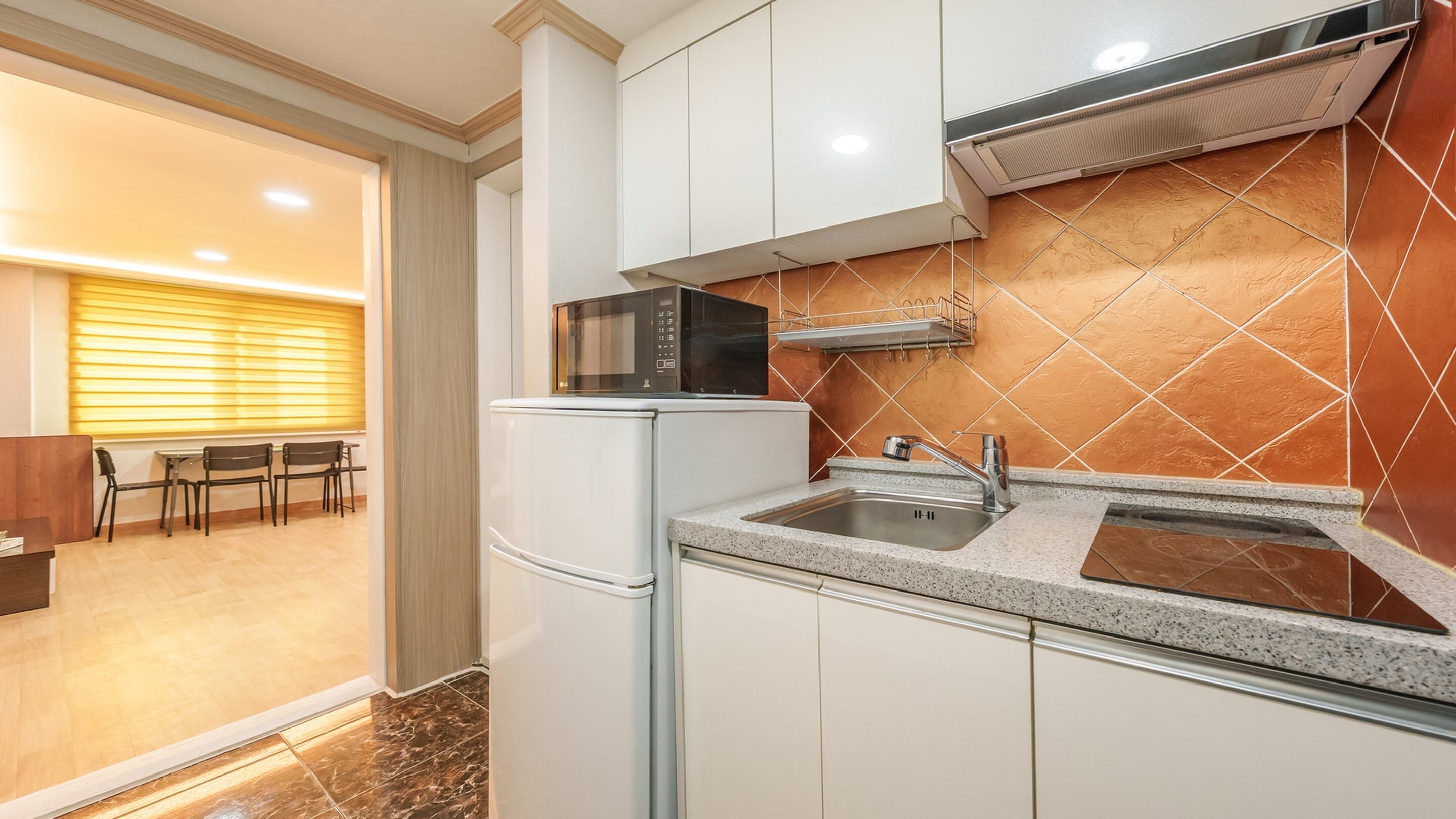 A modern kitchen with white cabinets, a stainless steel sink, and a microwave.