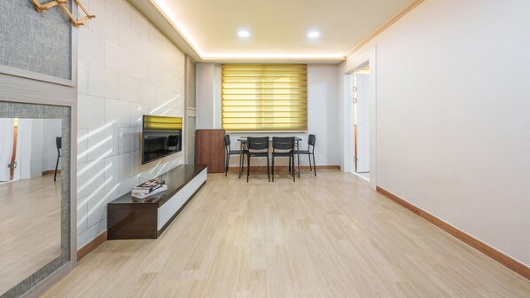 A modern living room with a flat-screen TV, a wooden coffee table, and a dining area with a table and chairs. - Boryeong The Daecheon Story Pension (Boryeong)