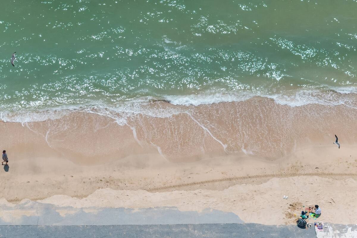 An aerial view of a beach with waves, sand, and people.