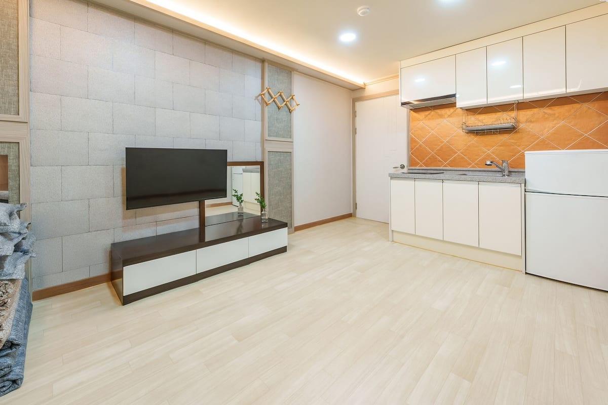 A modern kitchen with a built-in TV, white cabinets, and a tiled backsplash.