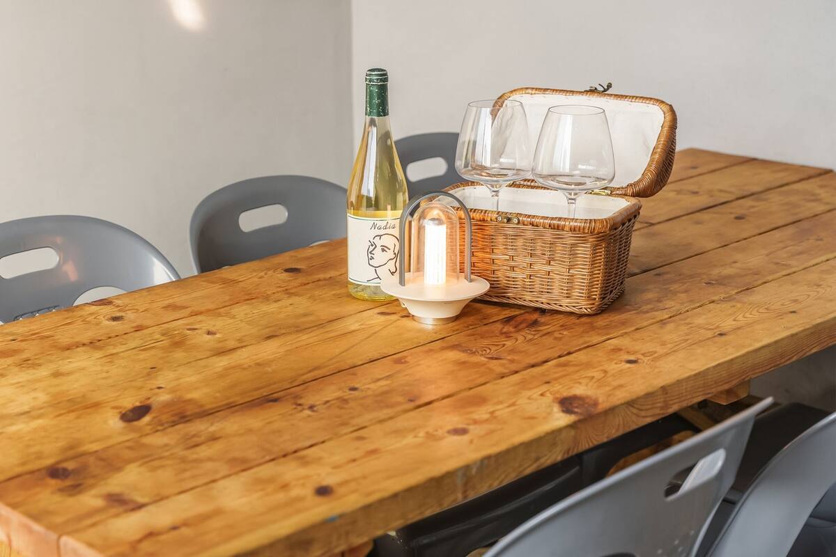 A wooden table with a bottle of wine, two glasses, and a candle.