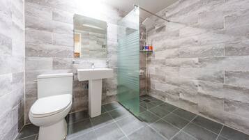 A modern bathroom with a toilet, sink, and glass-enclosed shower.