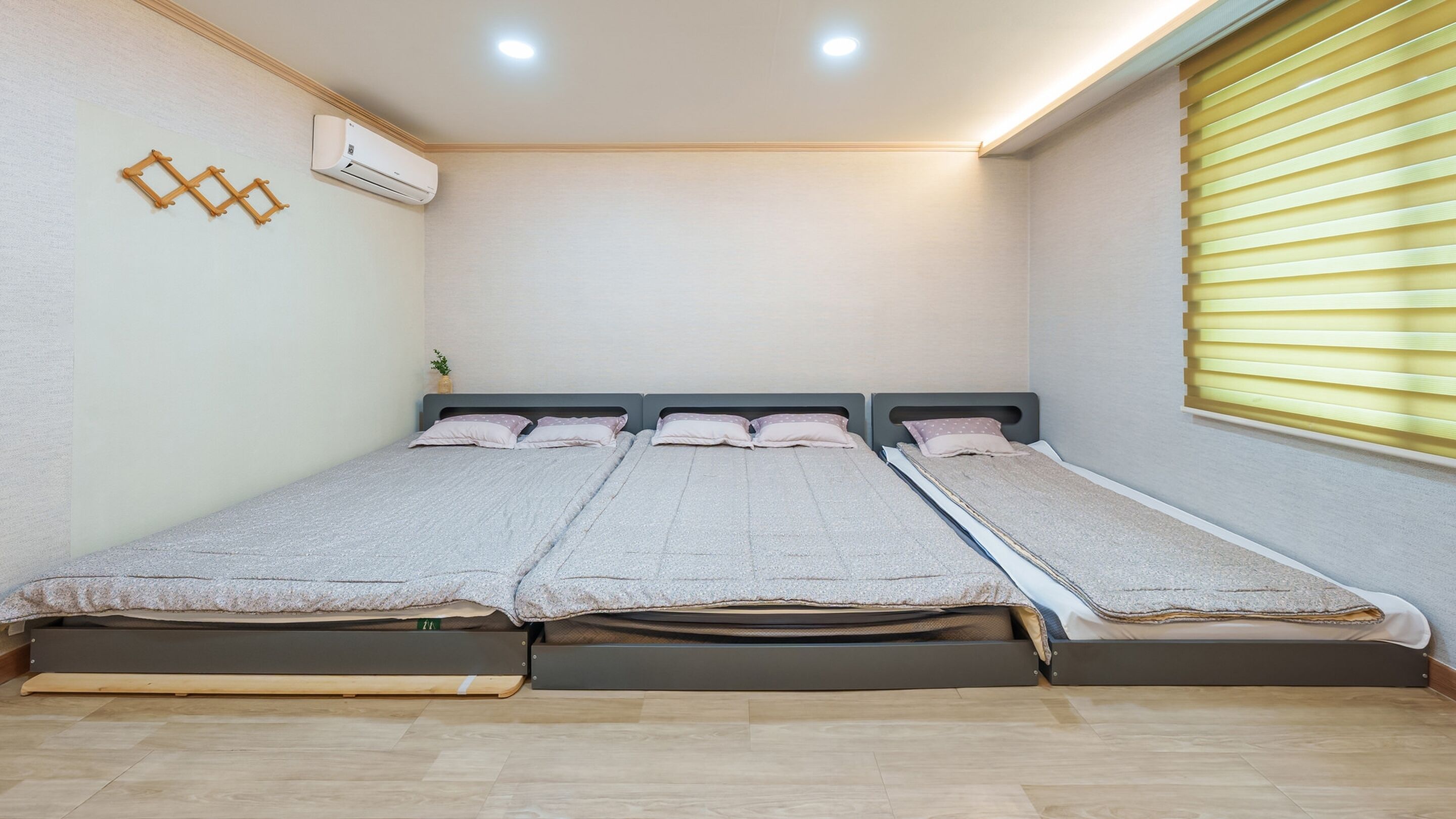 A room with a bed, an air conditioner, and a window with blinds.