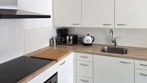 A modern kitchen with white cabinets, a wooden countertop, a stainless steel sink, a coffee maker, a toaster, and a kettle. - 1 bedroom lovely home in Heiloo (Heiloo)