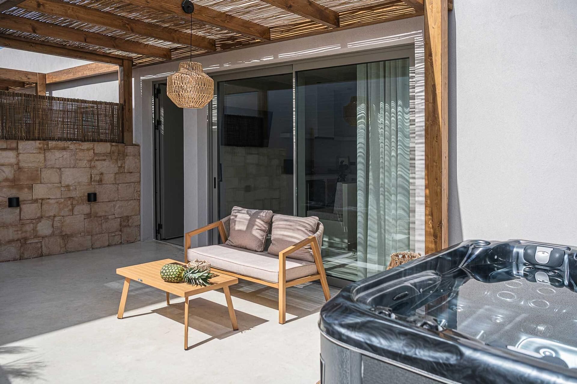 Un espace extérieur moderne aménagé avec une table en bois, un fauteuil rembourré et un jacuzzi.