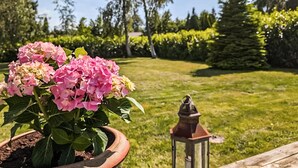 A garden with a potted pink hydrangea plant and a lantern on a wooden bench. - Gorgeous home in Væggerløse with WiFi (Væggerløse)