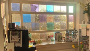 Eine Küche mit einem großen Fenster, einem Holzkasten, einem kleinen Tisch mit Obst und einer Vase mit Blumen.