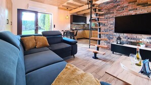 Ein modernes Wohnzimmer mit einem dunkelblauen Sofa, einem Holztisch und einer Wand mit Backsteinverkleidung.
