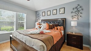 A bedroom with a bed, a nightstand, a wall-mounted lamp, and framed pictures. - Disney Escape - Private Pool & Full Resort Access (Kissimmee)