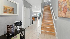 A hallway with a staircase, a guest book sign, and a map on the wall. - Disney Escape - Private Pool & Full Resort Access (Kissimmee)