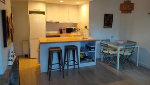 A compact kitchen with white cabinets, a microwave, a sink, and a small dining area with a table and stools. - Bright apartment with terrace & sea view (IB)