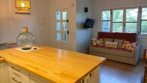 A kitchen with a wooden countertop, a glass bottle, and a wall-mounted TV. - Bright apartment with terrace & sea view (IB)