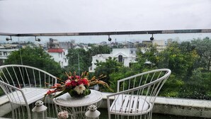 Un balcon avec deux chaises blanches et une petite table agrémentée d’un arrangement floral.