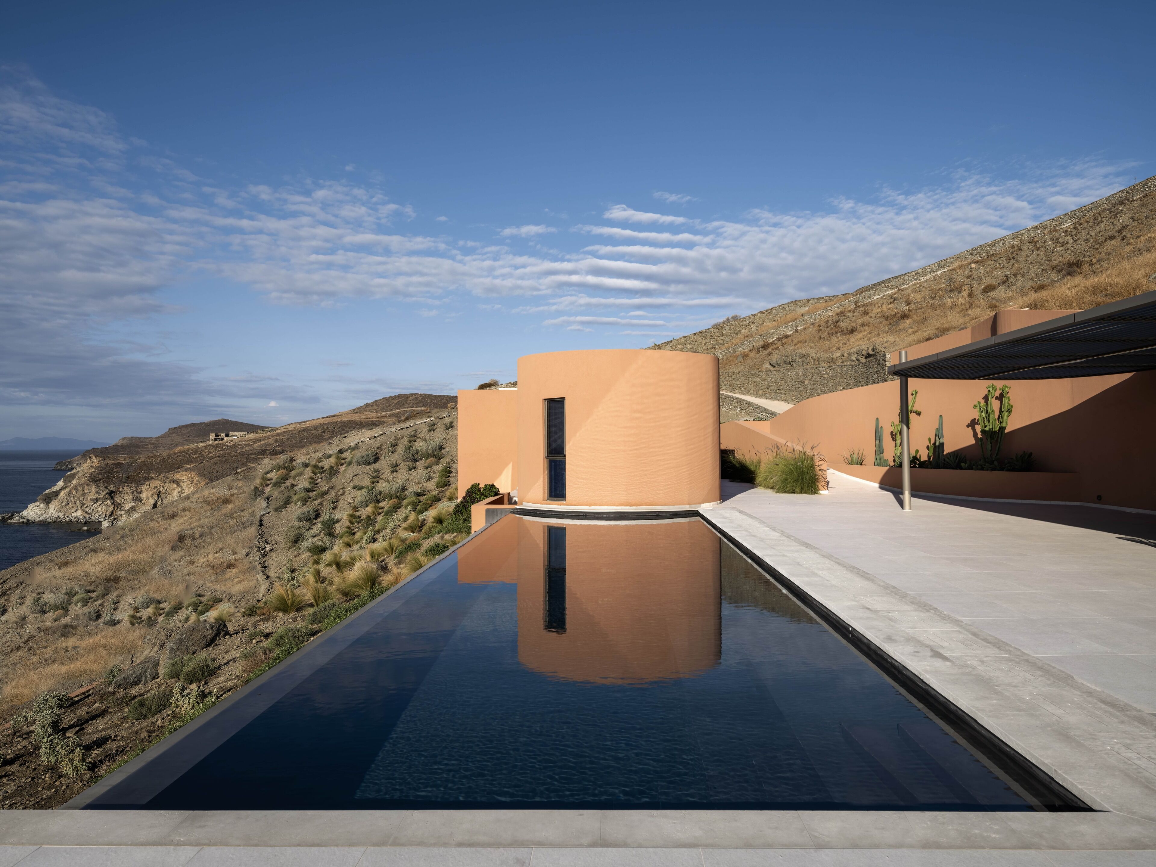 Une piscine moderne offrant une vue dégagée sur le paysage environnant, notamment une colline désertique et une étendue d’eau lointaine.